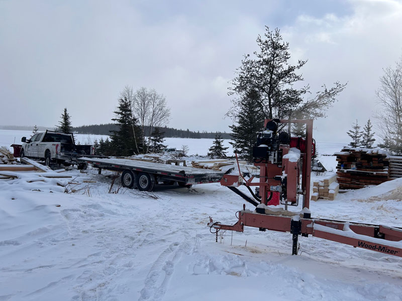 Truck with trailer, lumber and work equipment near frozen lake