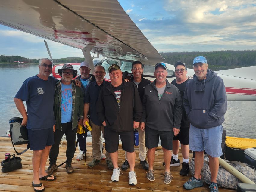 Halley's Camps Trapline Lake fishing group standing on the dock waiting to get on the plane. Smiling from the great fishing trip at Halley's Camps.