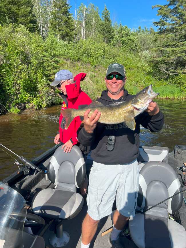 Dean holding up a trophy walleye in the sunshine.