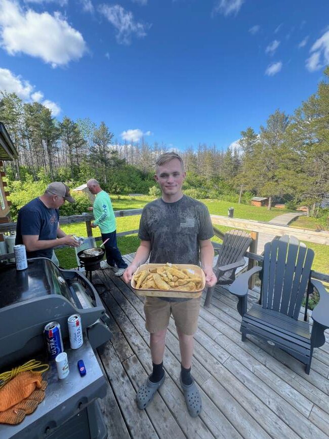 Young man holding tray of fried fish at Rex Lake Outpost.