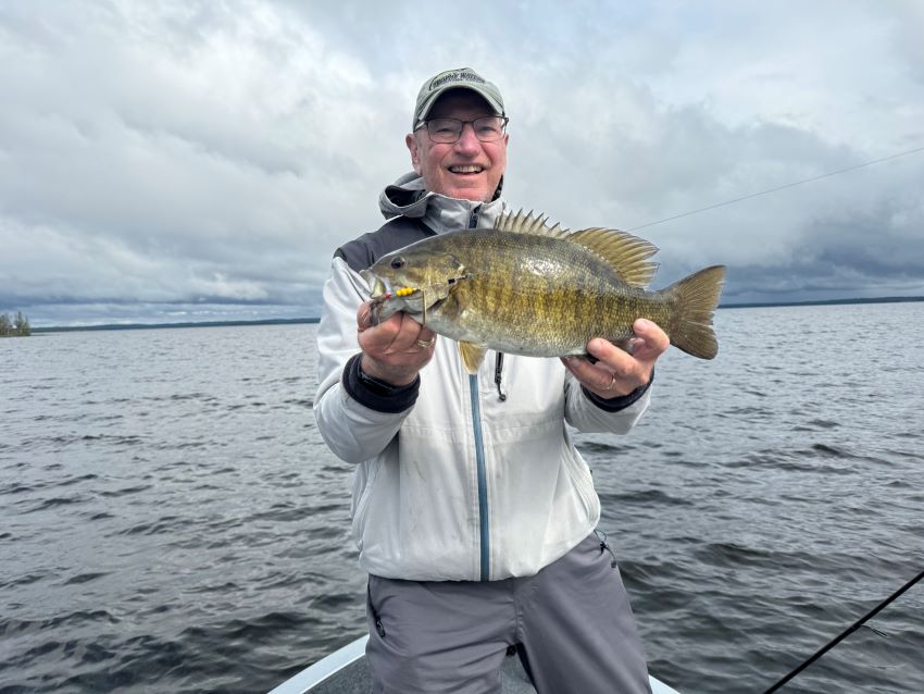 Don holding up a big fat smallmouth bass in a boat on the English River.