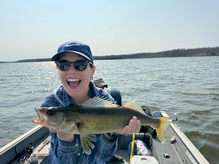 Woman holding up a WALLEYE in a Halley's Camps boat and she is beaming she's smiling so hard!!