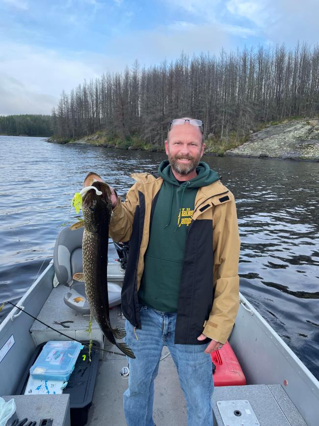 Fisherman holding up large northern caught out of a boat at Halley's Camps Rex Lake Outpost