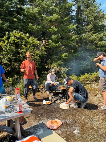 Guys helping prepare and fry fish and potatoes