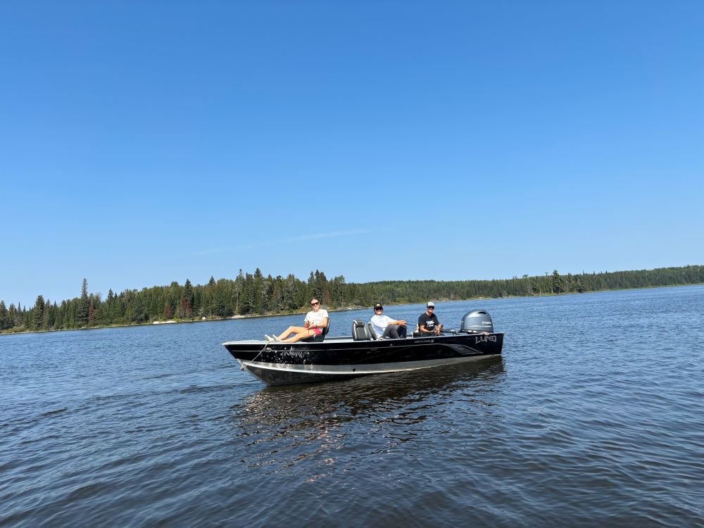 3 fishermen fishing out of a boat at Halley's Camps on the English River with blue skies