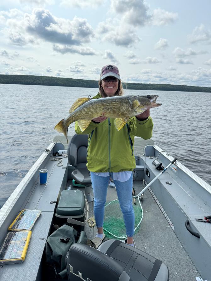 Trophy Walleye being held by a woman fisherman in a boat at Halley's Camps One Man Lake.