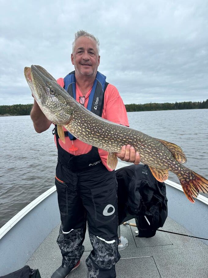 Fisherman and his trophy northern pike caught in a boat at Halley's Camps Kettle Falls Lodge.