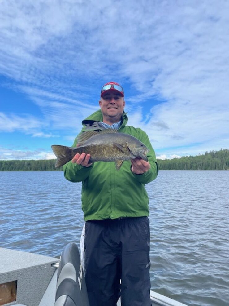 Man holding up Canadian trophy smallmouth bass at Halley's Camps. Fish is very big.