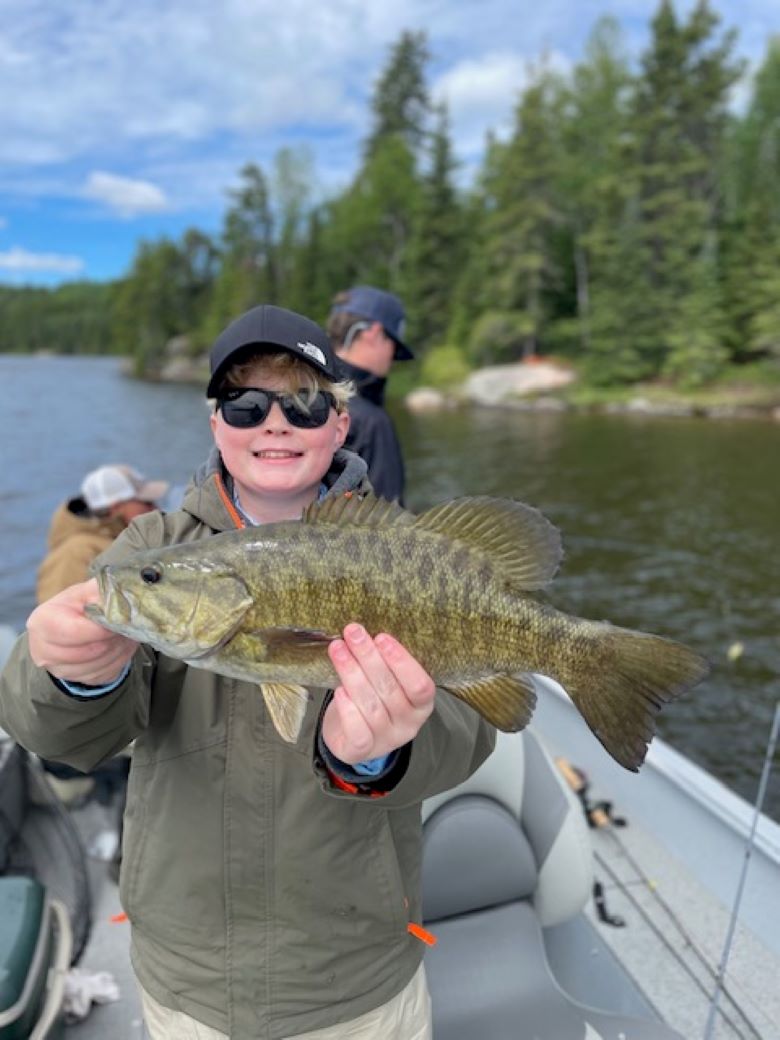 Fisherman holding up a big Canadian smallmouth bass at Halley's Camps One Man Lake.