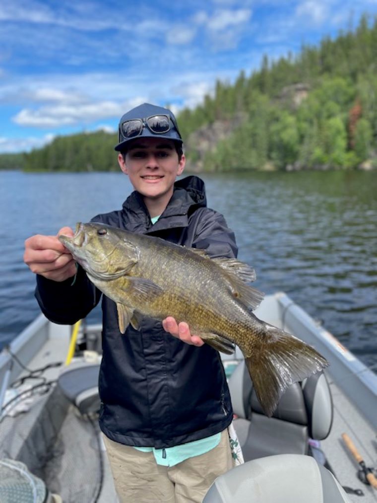 Young fisherman holding up smallmouth bass.