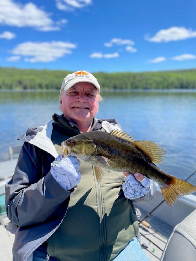 Grandfather on generational fishing trip holding smallmouth bass.