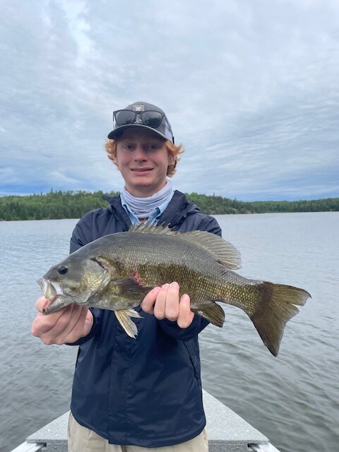 Fisherman holding up a smallmouth bass at Halley's Camps One Man Lake.