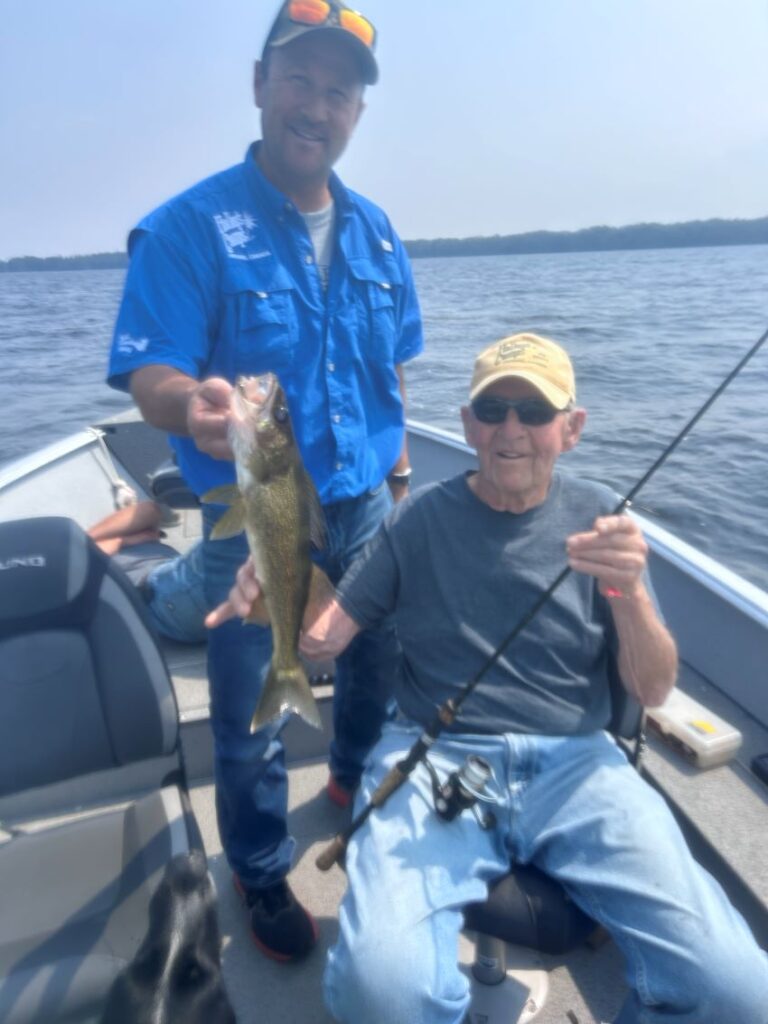 Grandson and grandfather fishing at Halley's Camps! Grandson is holding up his grandfather's catch! A walleye.