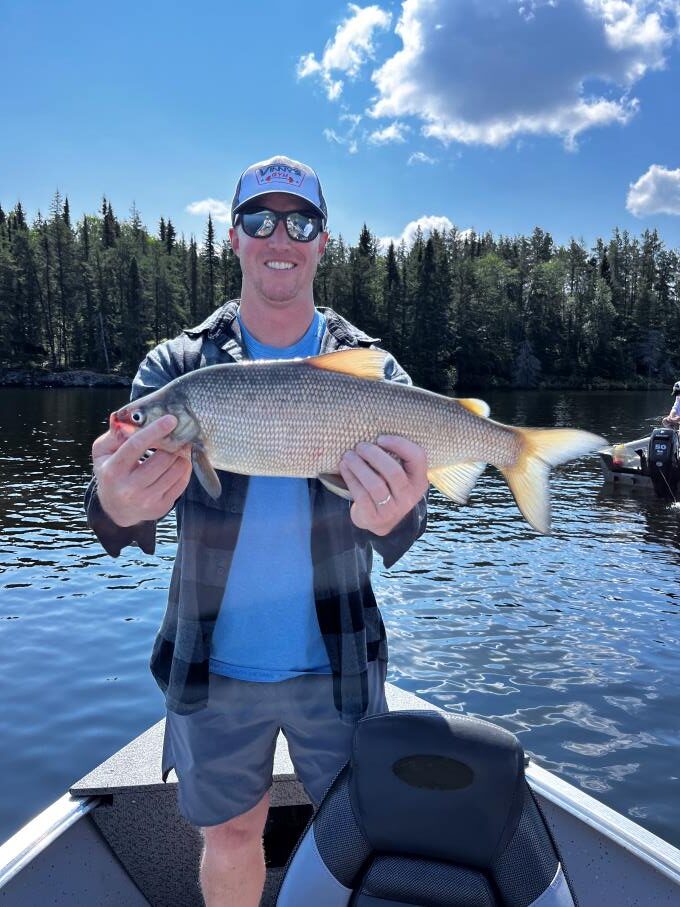 Man fishing in Halley's Camps boat holding white fish