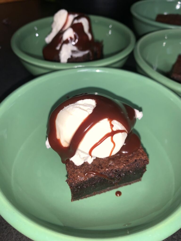 Pictured is a fudgy brownie, with ice cream and homeade fudge sauce drizzled over!