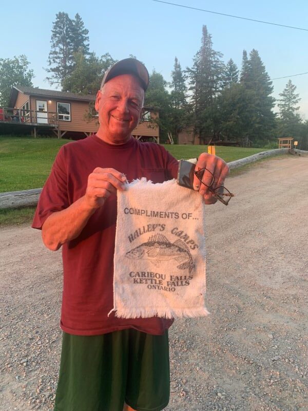 Fisherman holding up Halley's Camps complimentary fishing towel from 1990s.