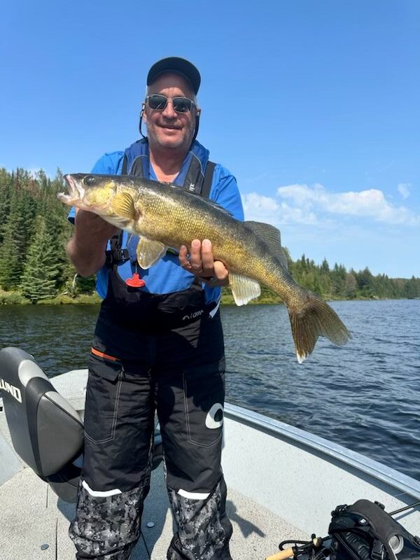 Fisherman and his Canadian trophy walleye caught in a boat at Halley's Camps Kettle Falls Lodge.