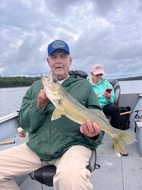 Bernie sitting in a boat holding his walleye