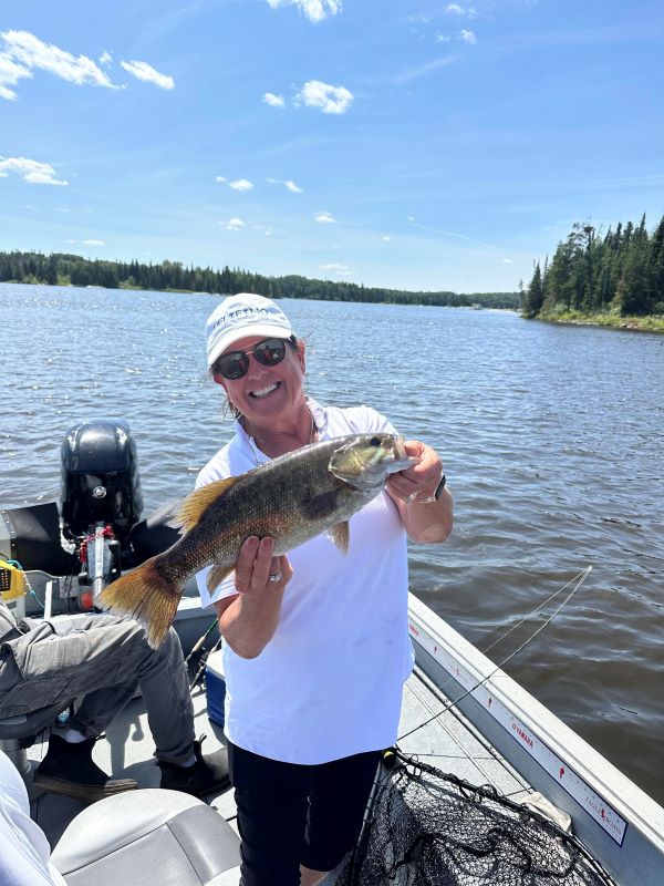 Lady holding a fish on a beautiful summer day at Kettle Falls Lodge.