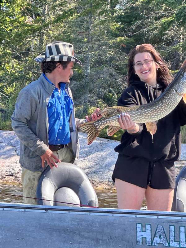 Girl fisherman with her guide in a boat fishing northern pike at Halley's Camps.