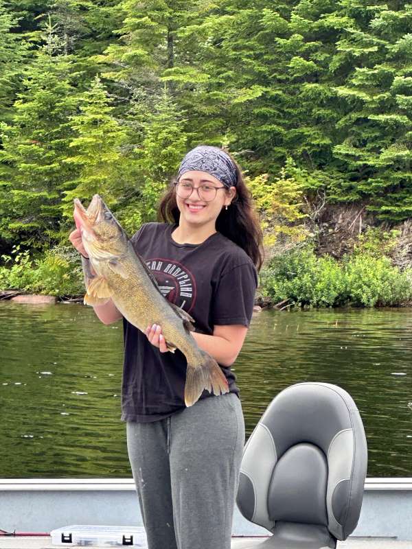 Woman holding a walleye in a boat on the English River at Halley's Camps!