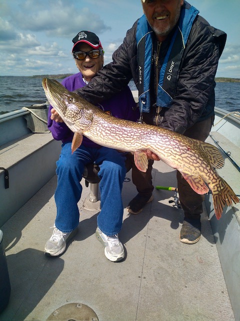 Grandma fishing from boat with guide holding her Canadian Trophy Northern Pike!