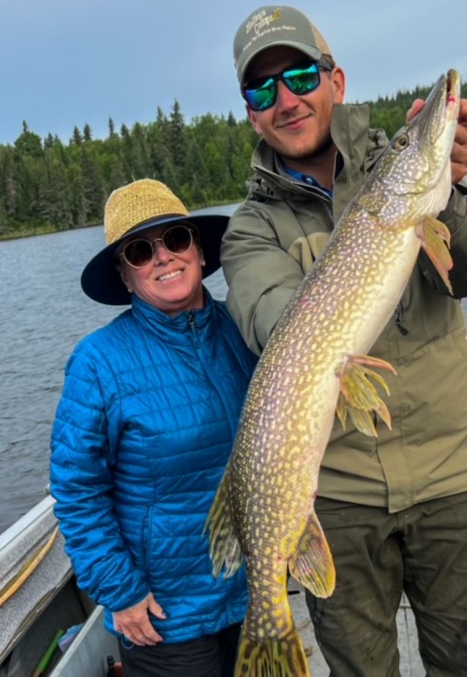 Woman posing with her guide holding her big Canadian northern pike!