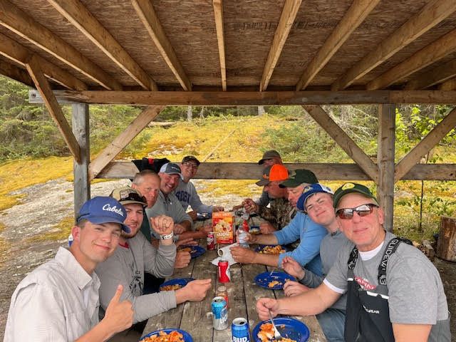 Fishermen group photo at shore lunch spot at Halley's Camps on the English River eating their fresh caught walleye!