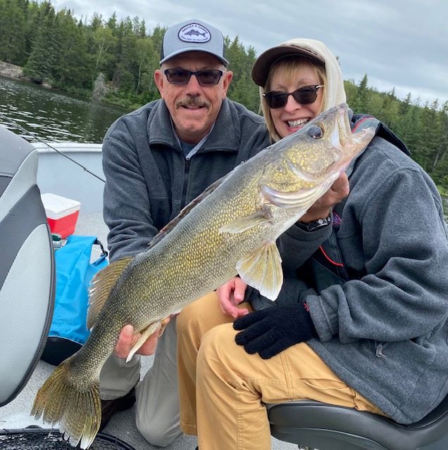 Husband and wife fishing walleye holding a fish in Halley's Camps fishing boat.