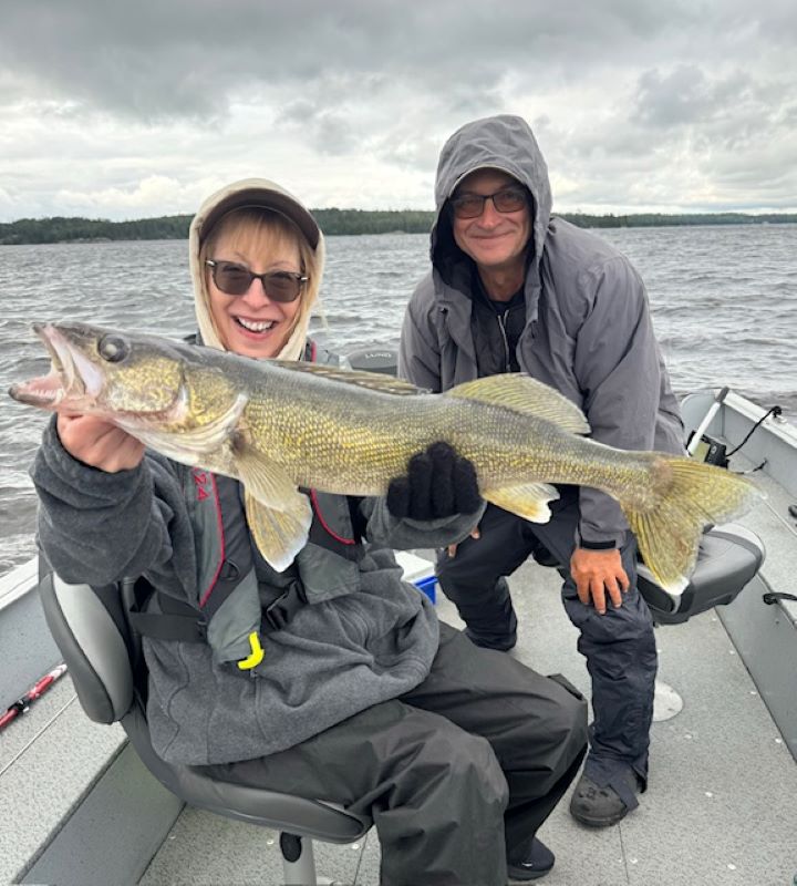 Wife holding walleye in Halley's Camps fishing boat on the English River, Canada