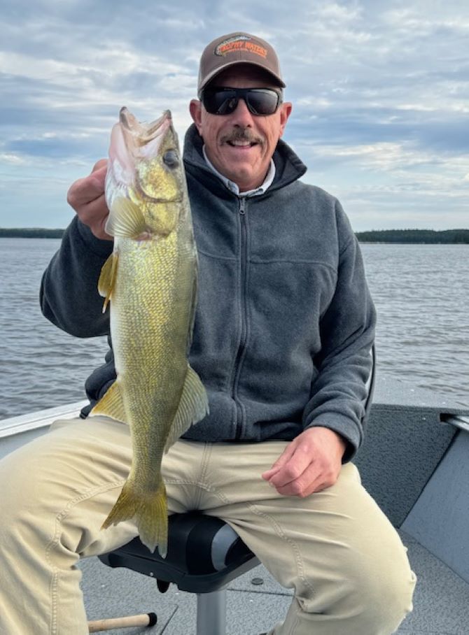 Jon holding a walleye in a Halley's Camps fishing boat on the Englsih River.