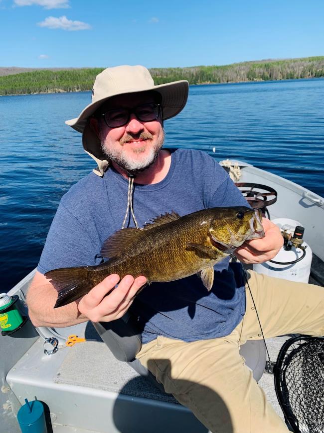 Fisherman holding smallmouth bass ion Halley's Camps Rex Lake's boat!