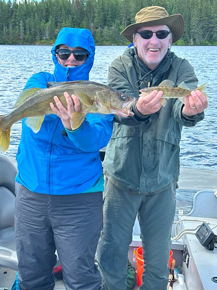 Steve and his daughter each holding a walleye, Steve's is little compared to his daughter's big catch!