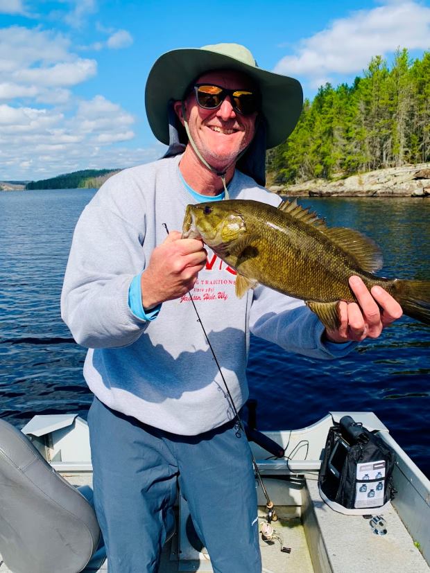 Fisherman holding big smallmouth bass with the sunshining!