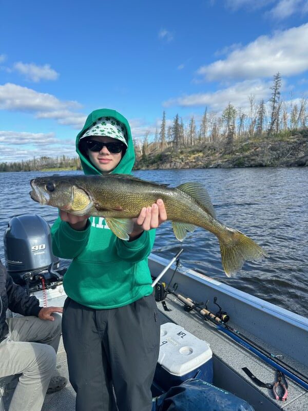 Young fisherman holding a Canadian Walleye in a Halley's Camps One Man Lake boat.