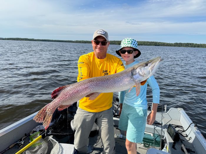 Young boy and fishing guide holding Canadian trophy pike in Halley's Camps boat.