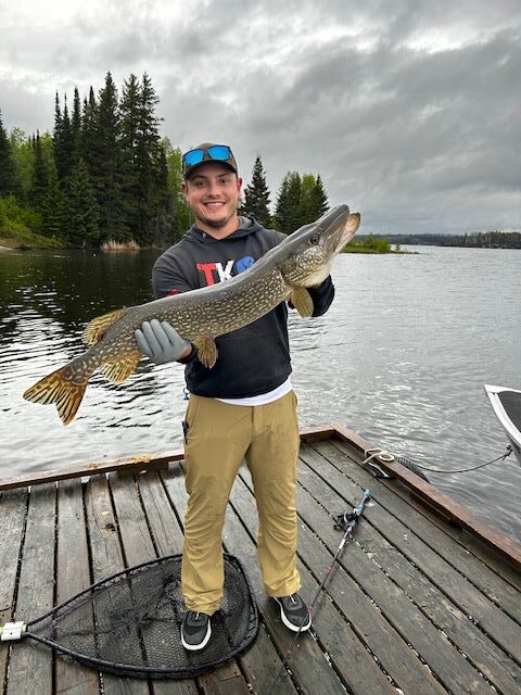 Young man fishing from the dock holding a trophy northern pike!