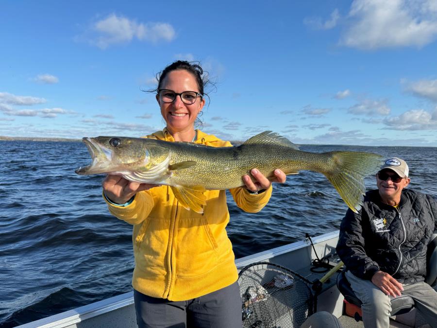 Lady fisherman holding up her Big Canadian Walleye in a Halley's Camps fishing boat