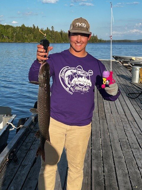 Man holding a fish he caught off the dock with a 3' Barbie fishing pole!