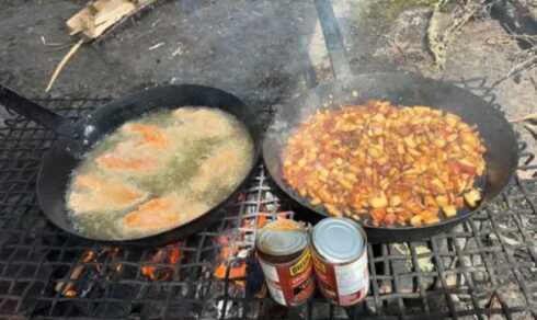 PIcture of a fry pan with fresh walleye and the other with fried potatoes and canned beans at shore lunch at Halley's Camps.