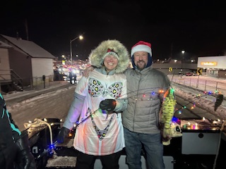 Man and Woman standing in a boat in a Christmas parade.