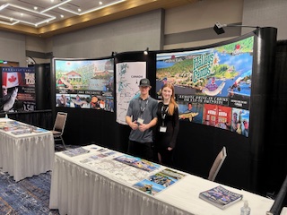 Man and woman standing in front of Halley's Camps sign at a sport show in Milwaukee.